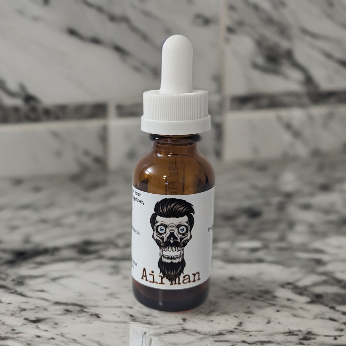 Airman beard oil in an amber dropper bottle with the Balboly bearded skull label