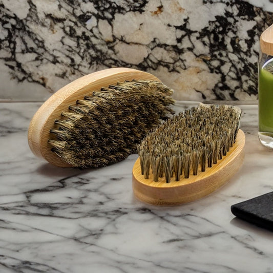 Oval beard brush with densely packed natural bristles on a wooden base