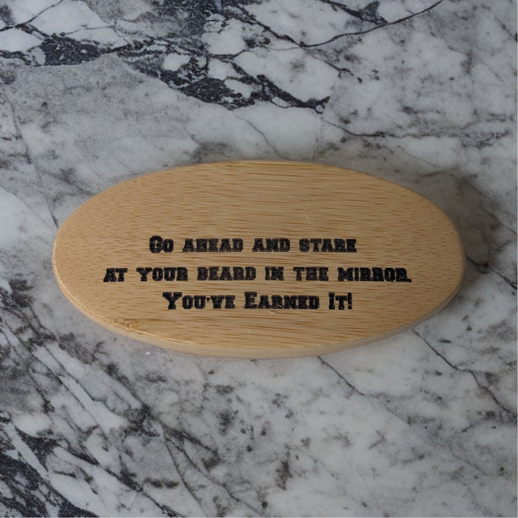 Personalized oval wooden beard brush with a custom engraving on marble